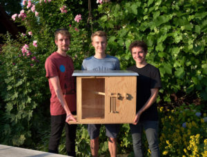 Drei Personen halten eine Bienen-Holzbox