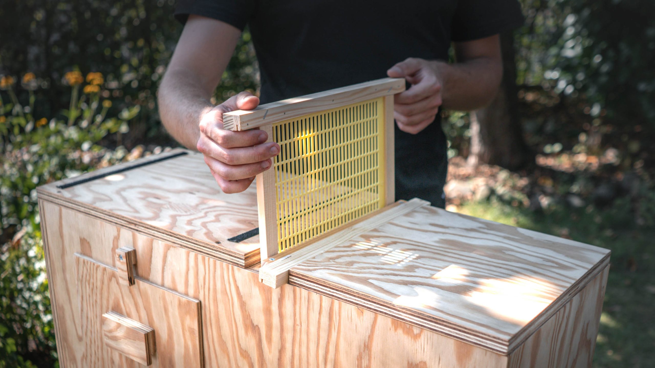 Person zieht einen Schieber aus dem Schiebersystem des Bienenkastens